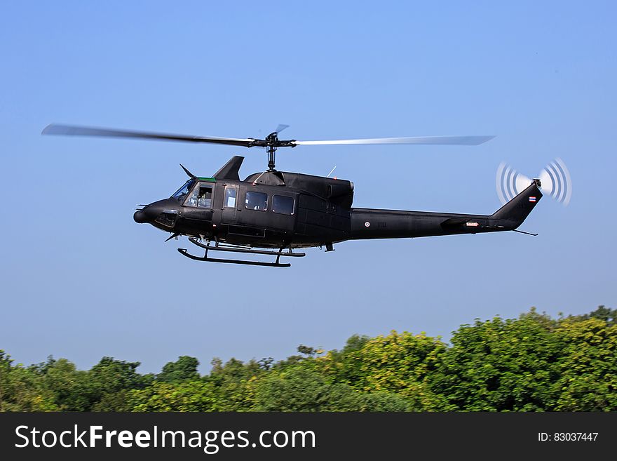 Black Helicopter Flying Above Green Trees