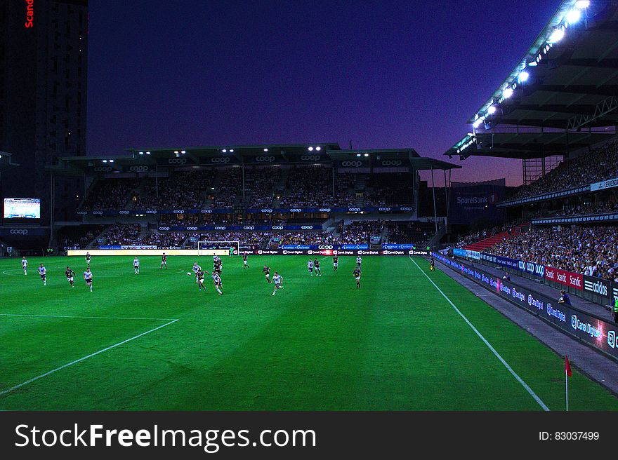 Game of football played at night in a floodlit stadium in front of a big crowd. Game of football played at night in a floodlit stadium in front of a big crowd.