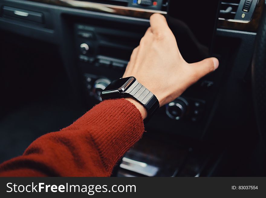 Smartwatch on arm with red sweater driving car.