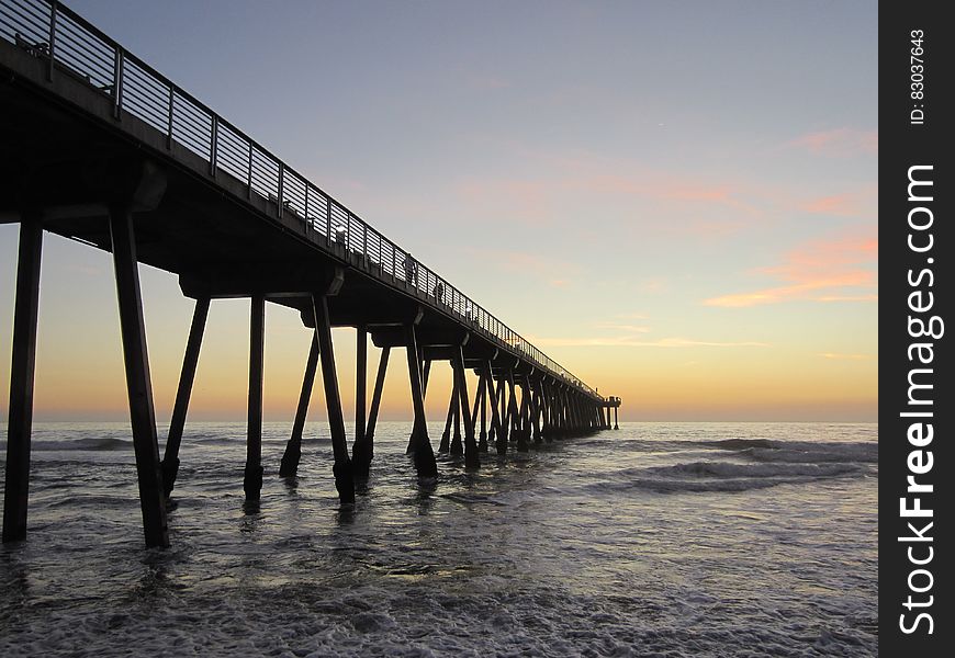 Pier in water at sunrise