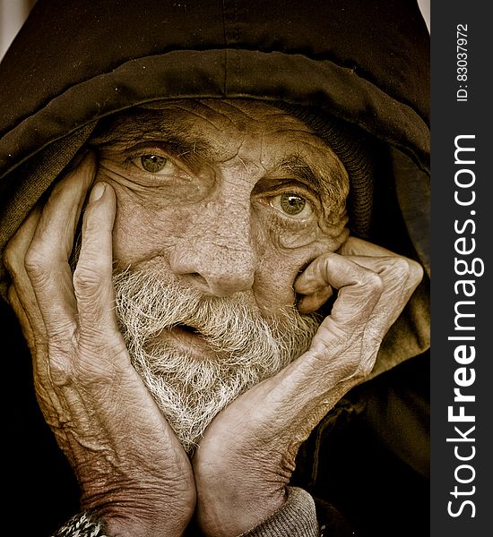 A close up portrait of an old man with a hood.