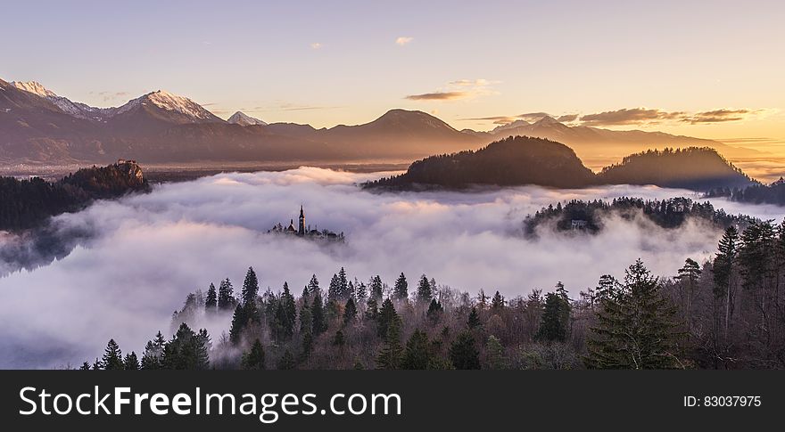 A misty morning landscape with forests and mountains.