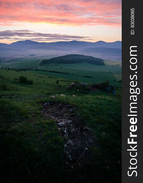 A sunset over green meadows with hills in the distance. A sunset over green meadows with hills in the distance.