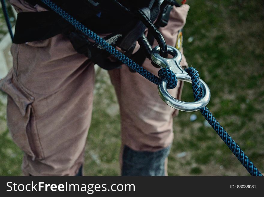 A rock climber with a rappelling rope and a ring attached to harness. A rock climber with a rappelling rope and a ring attached to harness.