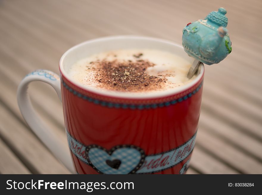 Red china coffee cup with latte and teapot decoration on spoon. Red china coffee cup with latte and teapot decoration on spoon.