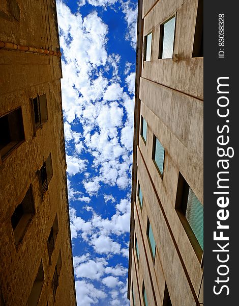 Low Angle Photography of Brown Concrete Building Under White Cloudy Blue Sky at Daytime