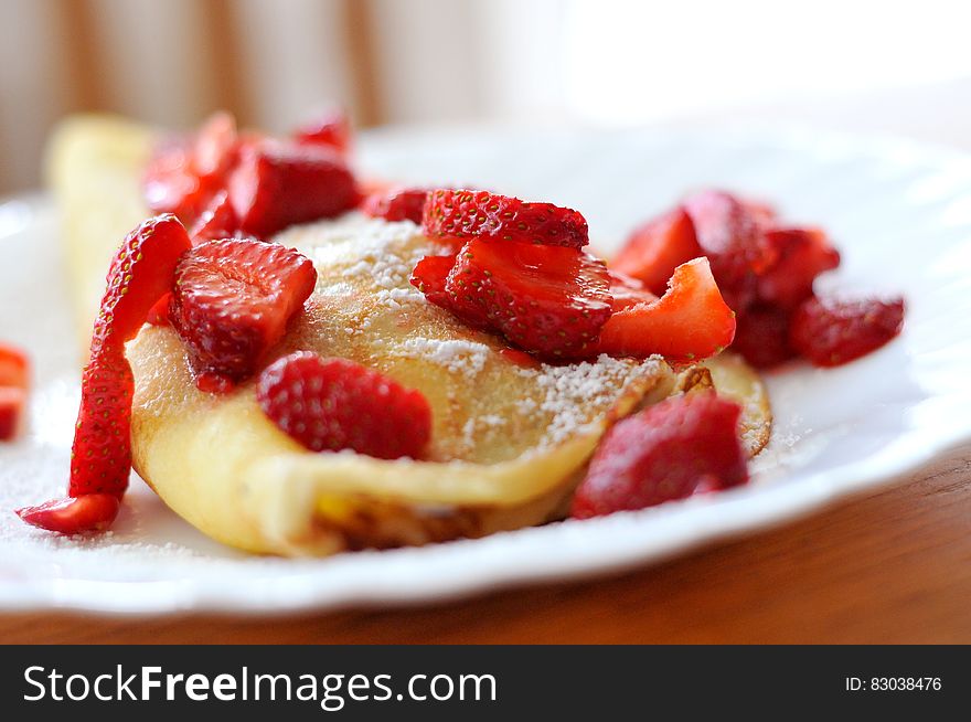 A plate of pancakes with fresh strawberries and powder sugar. A plate of pancakes with fresh strawberries and powder sugar.