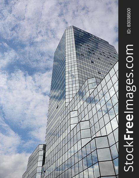 Facade of mirrored modern architecture against blue skies with white clouds. Facade of mirrored modern architecture against blue skies with white clouds.