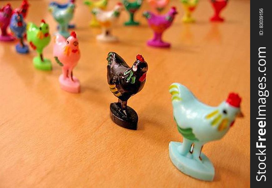 Colorful painted chicken or rooster figurines in line on wooden table. Colorful painted chicken or rooster figurines in line on wooden table.