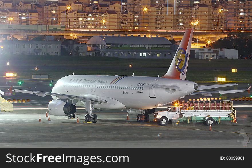 Commercial jet with fuel truck and airport workers on airport apron at night in city. Commercial jet with fuel truck and airport workers on airport apron at night in city.