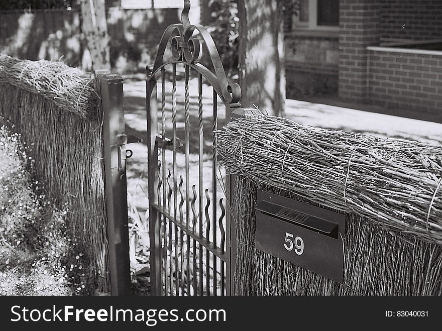Close up of thatched fence with metal gate outside home in black and white. Close up of thatched fence with metal gate outside home in black and white.
