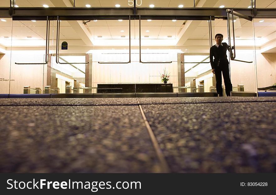 Man standing inside doorway to modern office building from low street level angle. Man standing inside doorway to modern office building from low street level angle.