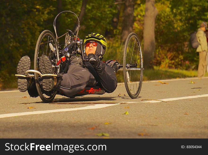 Man riding racing handcycle on roadway.