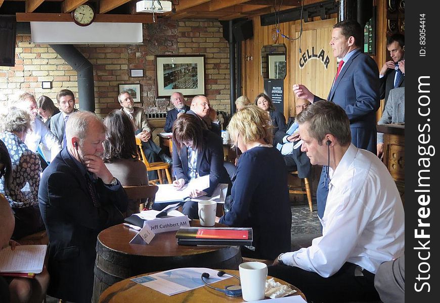 Man presenting to coworkers at business meeting held inside restaurant. Man presenting to coworkers at business meeting held inside restaurant.