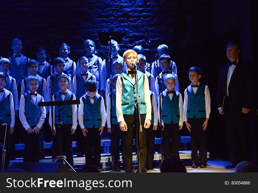 Solo singer with boys choir backup with director onstage during performance. Solo singer with boys choir backup with director onstage during performance.