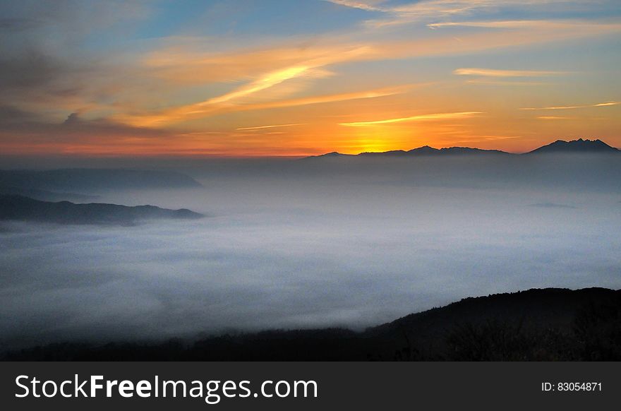 Sunset over horizon with mist covering mountain peaks. Sunset over horizon with mist covering mountain peaks.