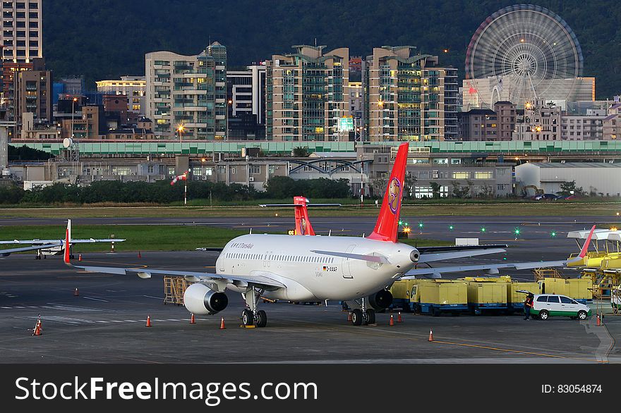 Commercial jets on runway of international airport illuminated at dusk.