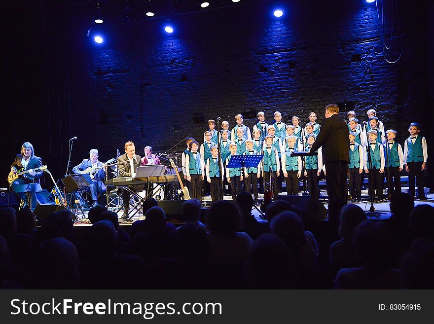 Boys choir with director onstage performing with musicians. Boys choir with director onstage performing with musicians.