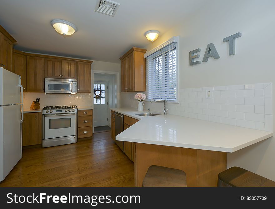 Contemporary kitchen with white appliances and wooden floors.