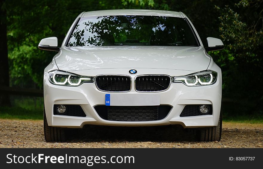 Close up of front of white luxury BMW automobile on country lane. Close up of front of white luxury BMW automobile on country lane.