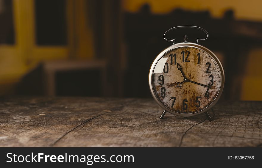 A rustic vintage alarm clock on a wood table. A rustic vintage alarm clock on a wood table.