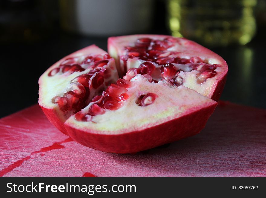 A halved pomegranate fruit on a cutting board. A halved pomegranate fruit on a cutting board.