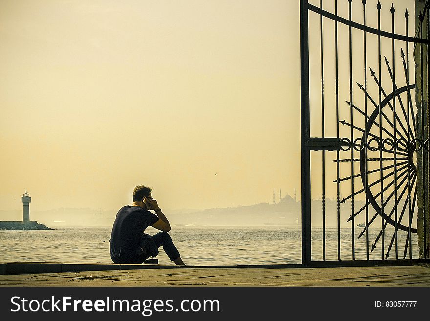 A man sitting on the pier at the harbor. A man sitting on the pier at the harbor.