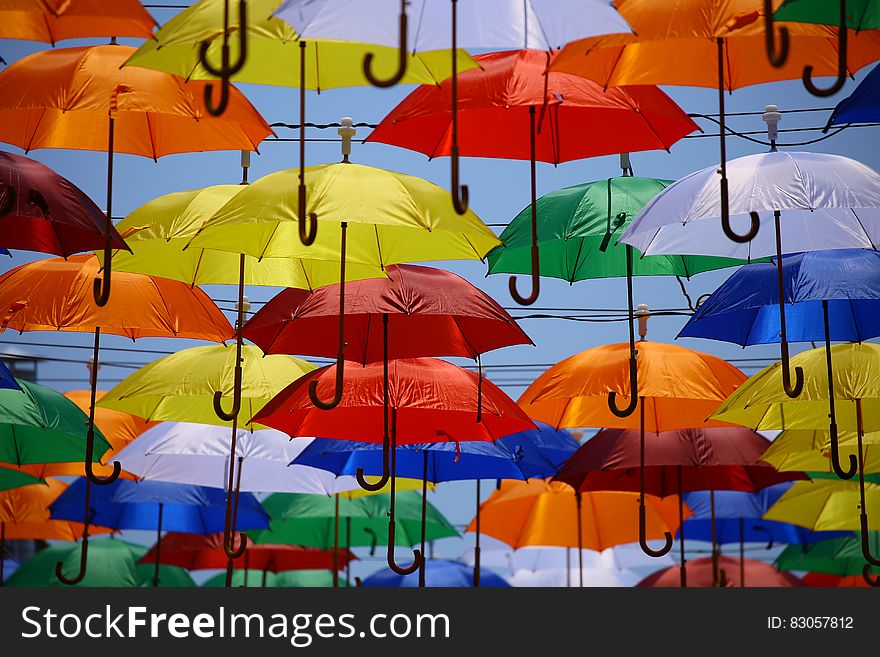 Colorful umbrellas hanging from lines on top of a street.