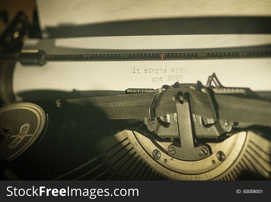 A vintage typewriter with the text "it starts with one WORD" written on a sheet.