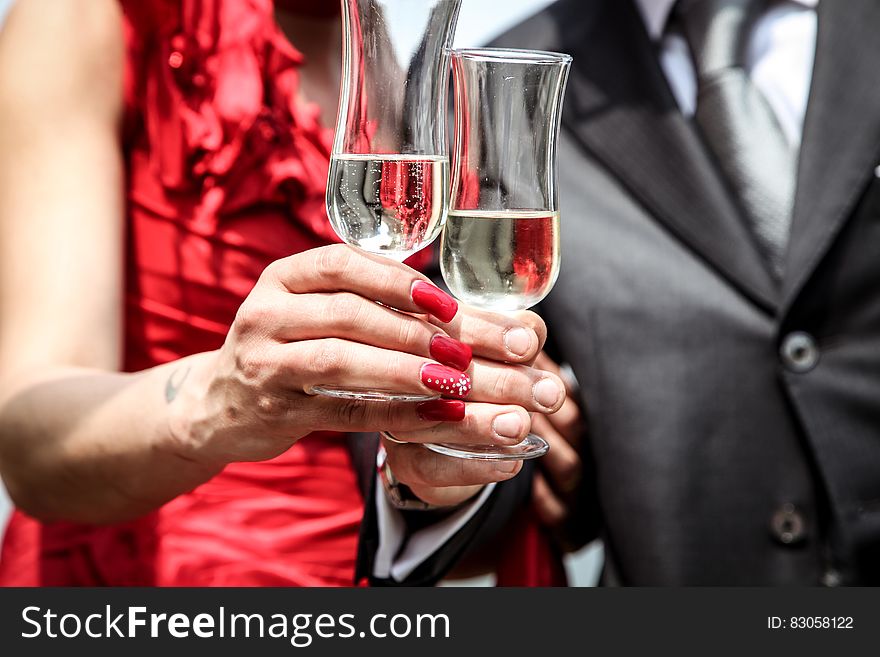 Hands and bodies of newly married couple toasting with champagne glasses.