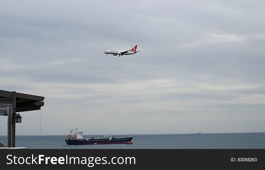 White Plane Flying Above Black Ship