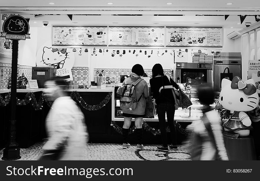 2 Women Standing Infront Hello Kitty Themed Store in Greyscale Photography