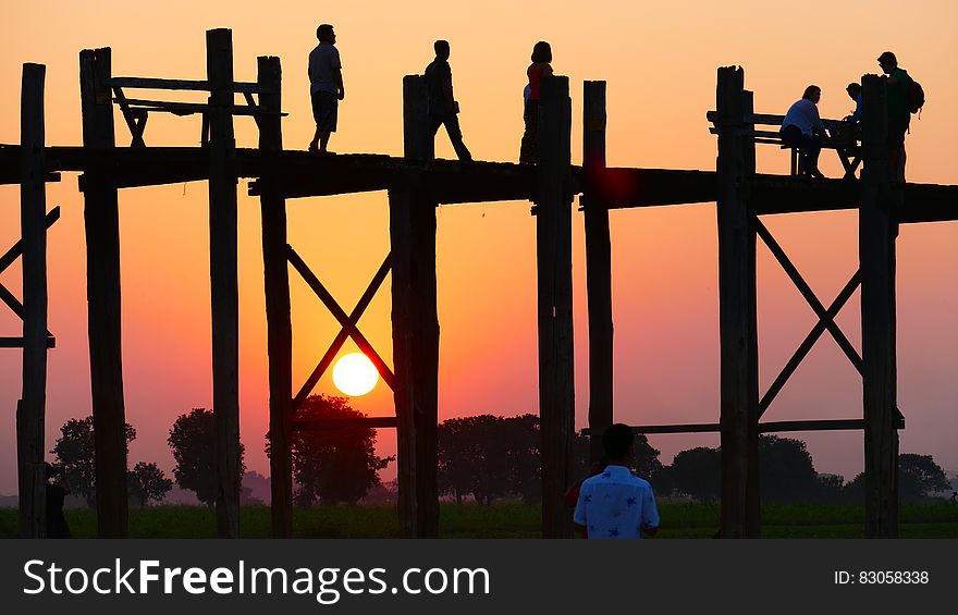 People Standing on a Bridge during Sunset .