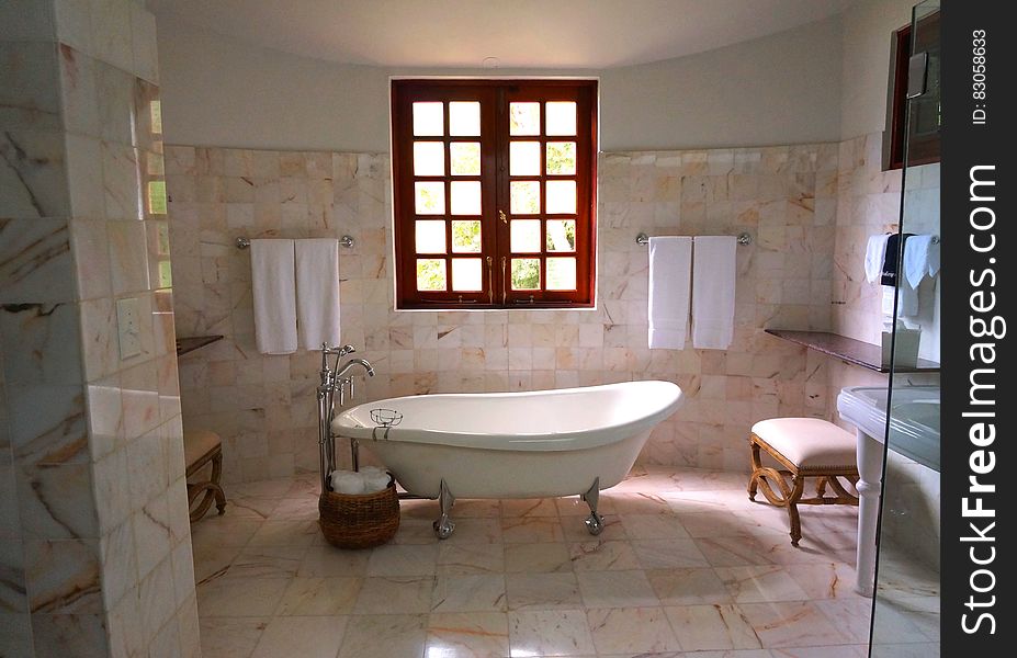 White Bathtub on White Tile Bathroom Near Brown Framed Clear Glass Window