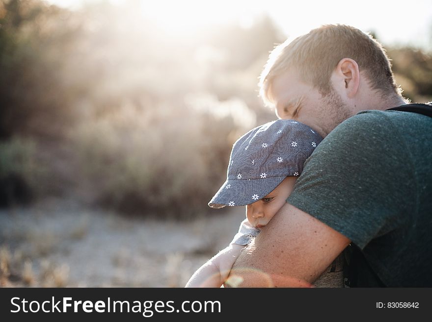 Man Hugging The Baby In Blue Floral Fitted Cap During Daytime