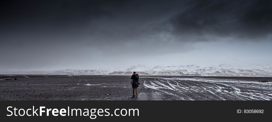 Man Standing on Gray Dessert Under Gray Cloudy Sky during Daytime