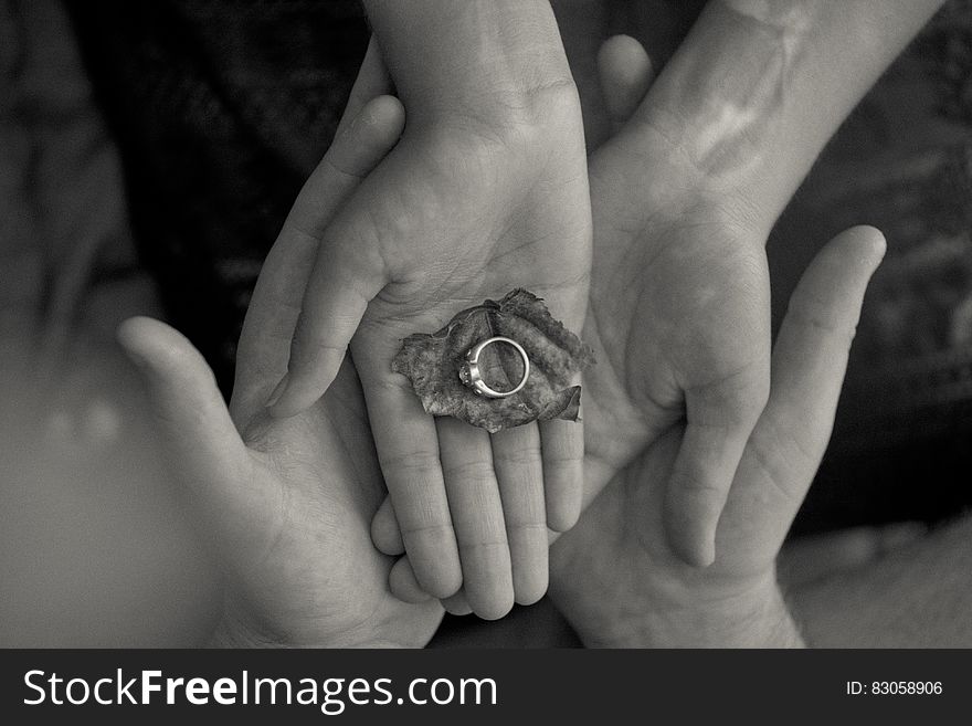 Person Holding Leaf and Ring in Grayscale