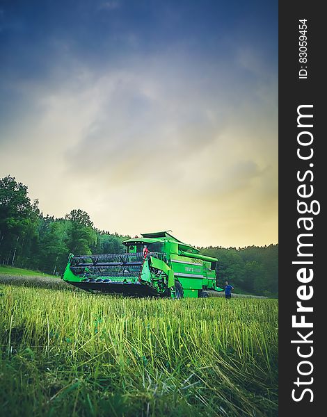 Green Harvester on Green Rice Field Under Blue and White Sky during Daytime