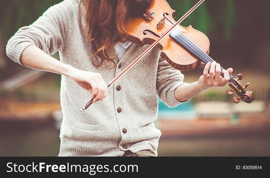 Woman in Gray Cardigan Playing a Violin during Daytime