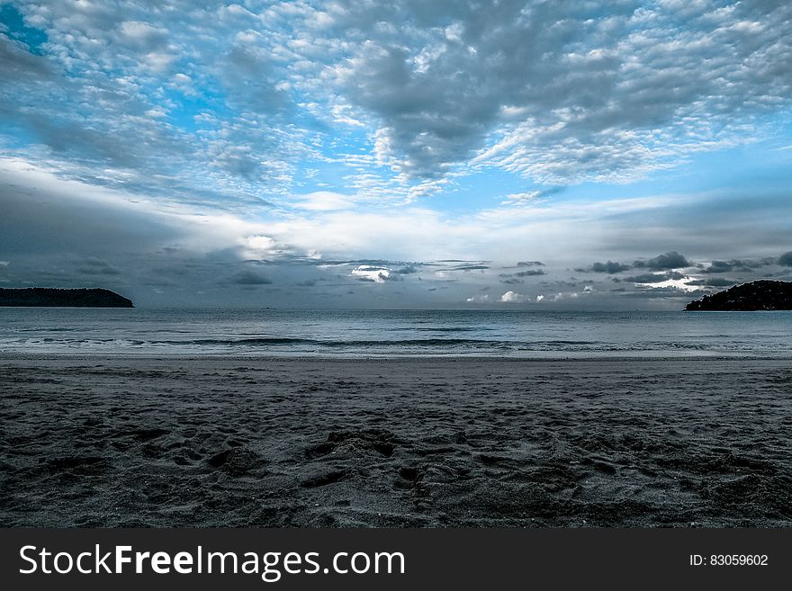Gray Sand on Sea Shore Under Cloudy Sky during Daytime