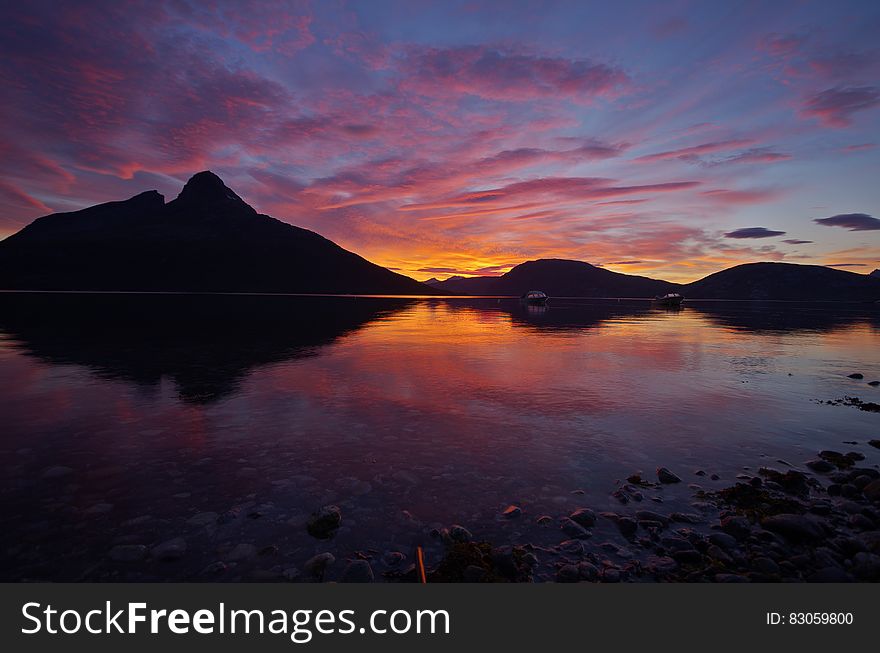 A lake with mountains in the distance with sunset skies. A lake with mountains in the distance with sunset skies.