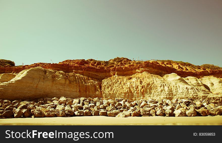 Rocks and cliff along sandy beach on sunny day. Rocks and cliff along sandy beach on sunny day.