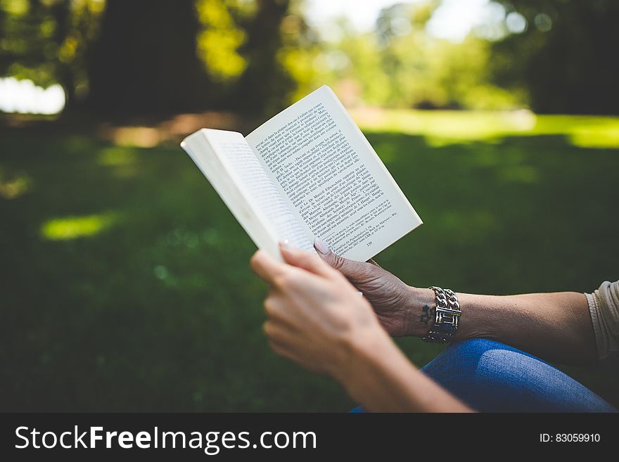 Person Holding And Reading Book During Daytime