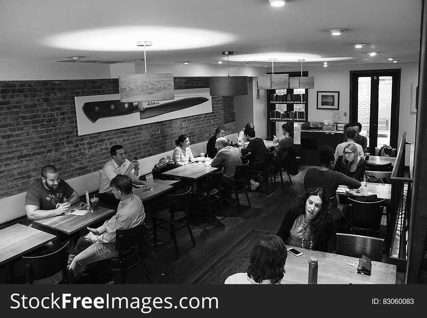 A black and white photo of people sitting and chatting in a cafe bar. A black and white photo of people sitting and chatting in a cafe bar.