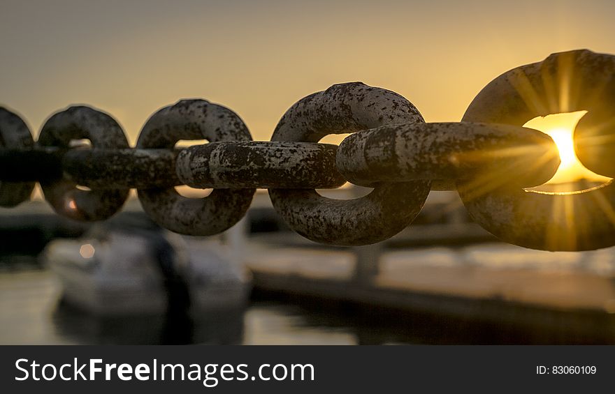 A close up of a rusty dock chain at sunset.