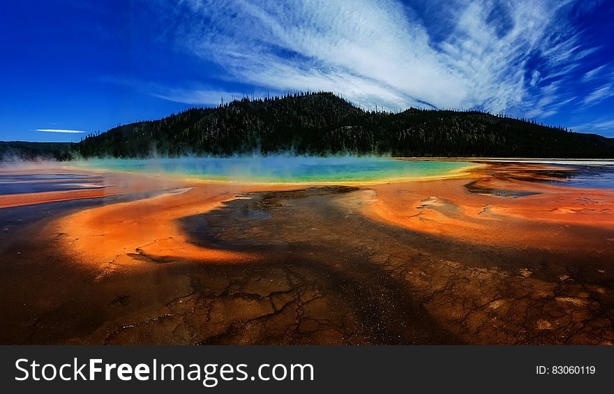 Green Forested Mountain and Hot Spring Under Blue Sky