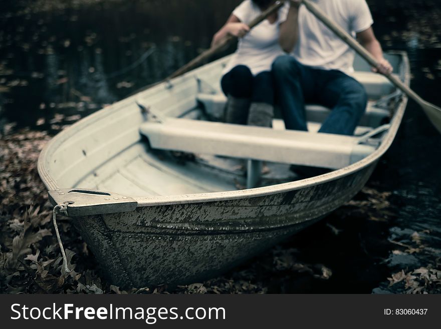 Man and Woman Sitting on Boat Holding Paddles