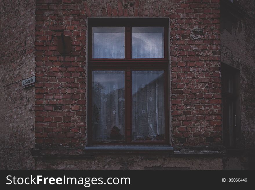 Lace curtains in window on outside brick wall. Lace curtains in window on outside brick wall.