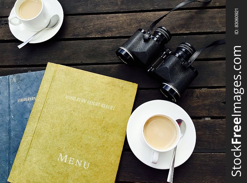 White Ceramic Tea Cup on White Saucer Near Menu Book