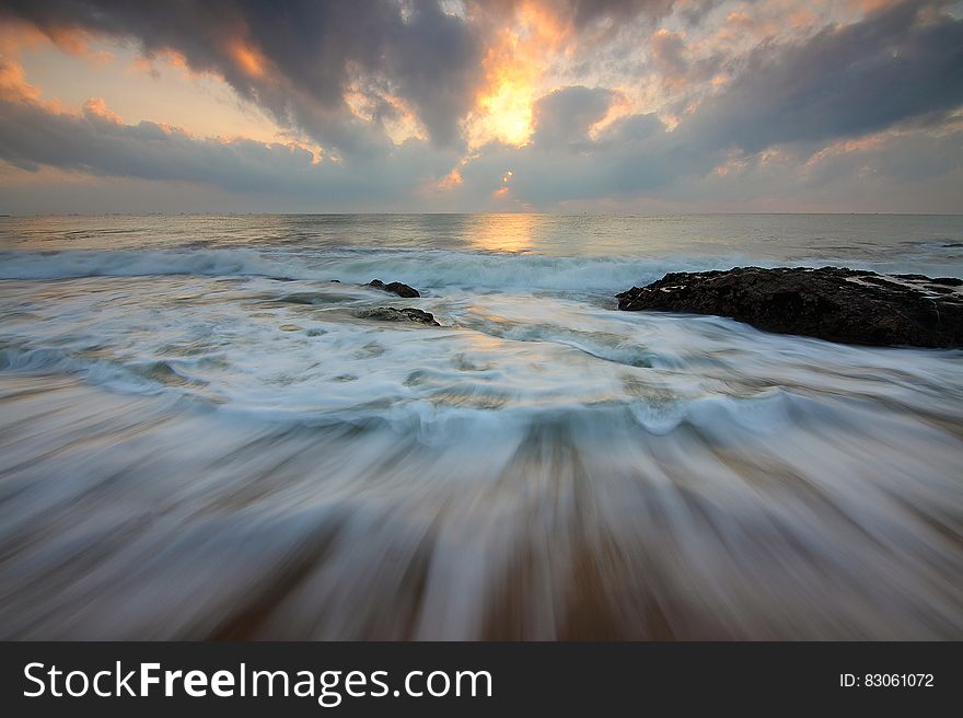 Time Lapse Photo of Water Current and Brown Rock Under White and Yellow Cloudy Sky